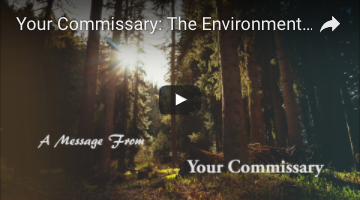 Screenshot of the Environment video. A forest scene with a bright sunny sky has the words "A message from your commissary" over it in white.