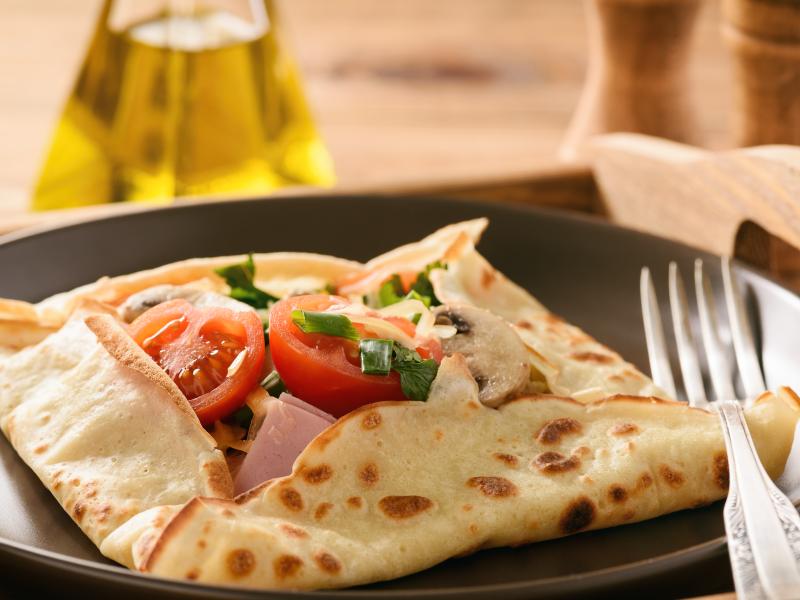 Crepe folded into a square with tomatoes cheese and ham filling