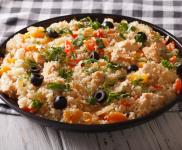 Bowl of couscous with canned tuna, olives, walnuts, and peppercinis.